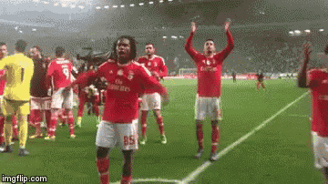a group of soccer players are standing on a field with their hands in the air .
