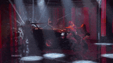 a woman singing into a microphone in front of a car with #kimmel written on the screen