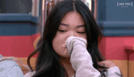 a close up of a woman covering her nose with her hand