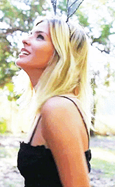 a woman wearing bunny ears and a black dress looks up