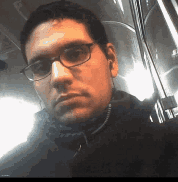 a man wearing glasses and ear buds is taking a selfie