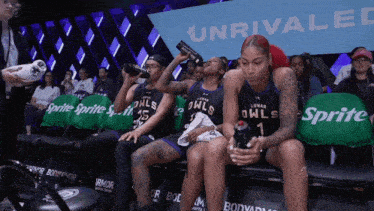 a group of female basketball players are sitting on a bench with sprite chairs