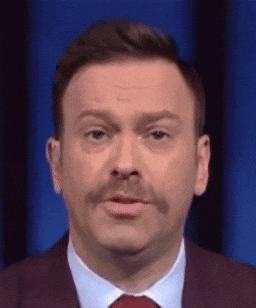 a man with a mustache wearing a suit and tie is making a funny face .