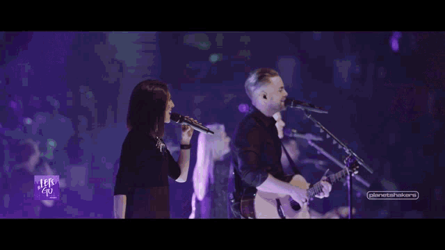 a man playing a guitar and a woman singing on a stage with a sign that says ' texas go ' on it