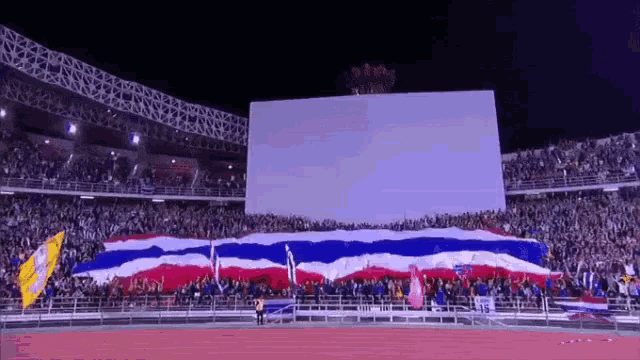 a crowd of people in a stadium with a large white board in the background