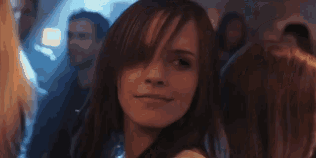 a woman in a white dress is smiling in front of a crowd of people at a party .