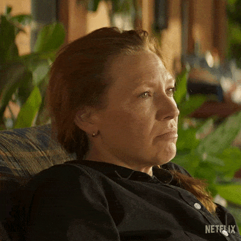 a woman with red hair is sitting in a chair with her eyes closed and a sad look on her face .