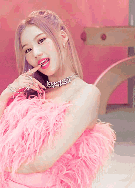 a woman wearing a pink feathered dress and a necklace that says " east "