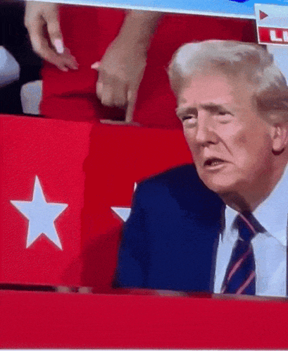 a man in a suit and tie is sitting in front of a red and white star