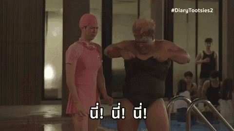 a man in a pink dress is standing next to a fat man in a swimsuit .