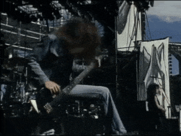 a man is playing a guitar on a stage in front of a sign that says x
