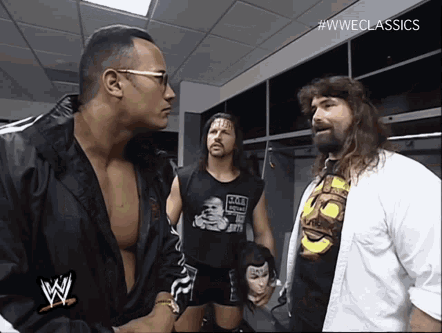 three wrestlers are standing in a locker room and one of them is wearing a shirt that says wwe
