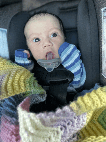 a baby is in a car seat with a pacifier in his mouth