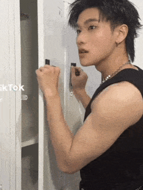 a man in a black tank top is standing next to a locker with tiktok written on it