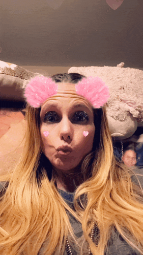 a woman with long blonde hair and pink hearts on her face makes a funny face