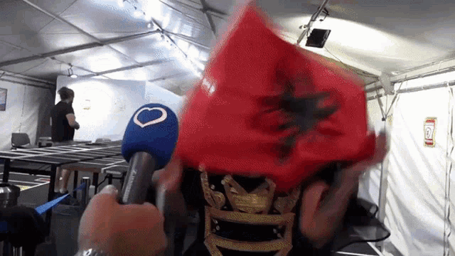 a person is holding a red flag in front of a microphone with the letter o on it