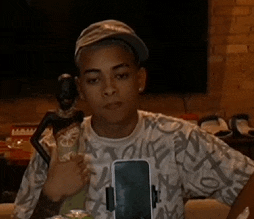 a young man holding a statue and a cell phone while wearing a hat