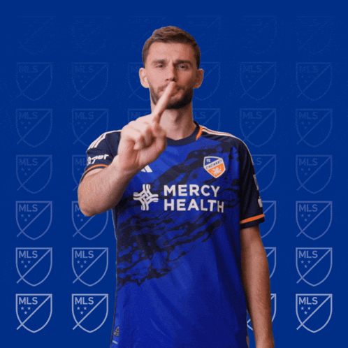 a man in a blue mercy health jersey holds up a finger