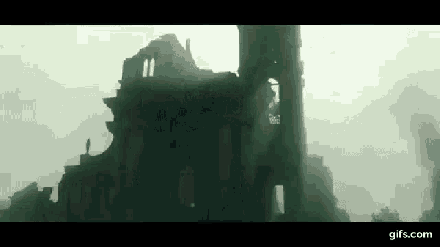a ruined building with a tower in the background and a person standing on top of it .