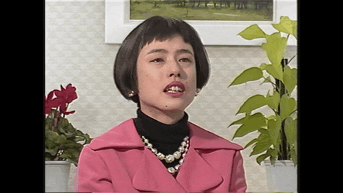 a woman in a pink coat and pearls necklace