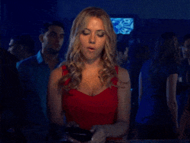 a woman in a red dress is standing in a crowd holding a piece of paper that says ' a ' on it