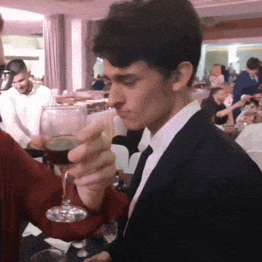 a man in a suit holds a glass of wine in his hand