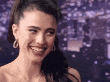 a woman wearing hoop earrings and a necklace smiles