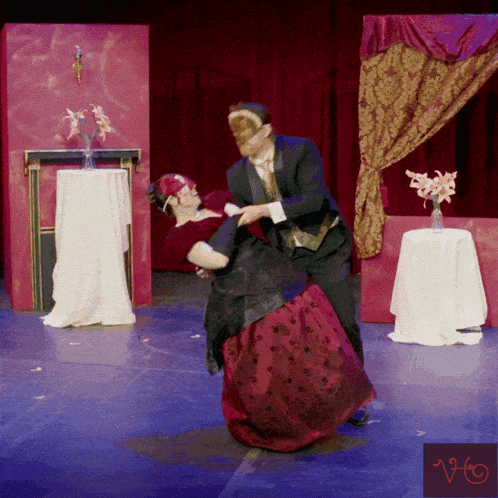 a man in a mask is dancing with a woman in a red dress and gloves