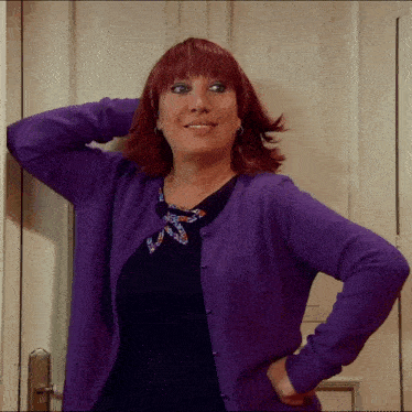 a woman with red hair is wearing a purple cardigan and a black top