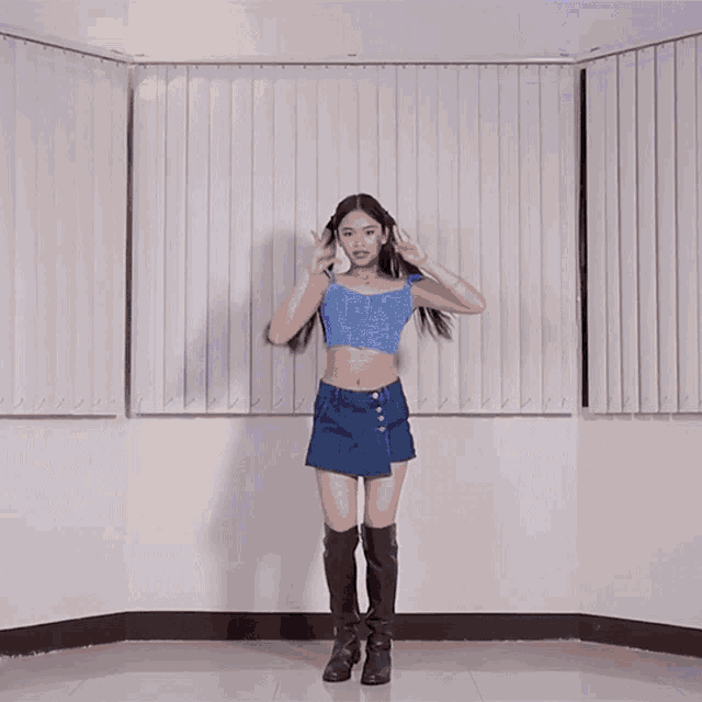 a woman in a blue crop top and denim skirt is dancing