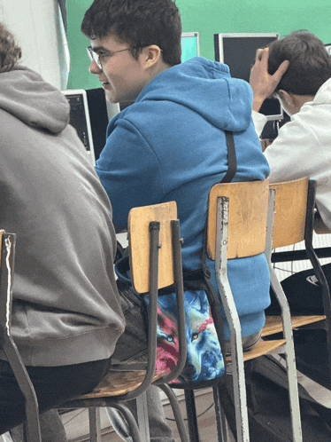 a boy in a blue hoodie sits in a chair