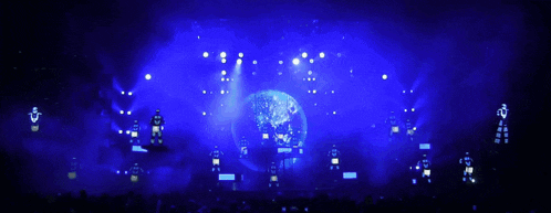 a crowd of people watching a concert with blue lights behind them