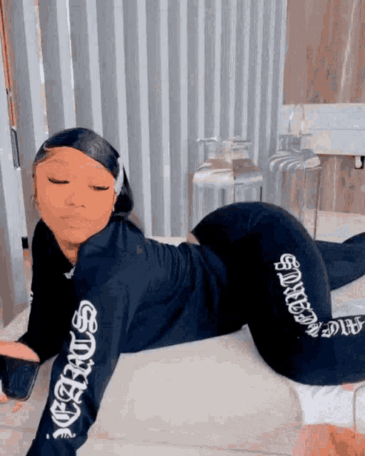 a woman in a black outfit is laying on her stomach on a bed .