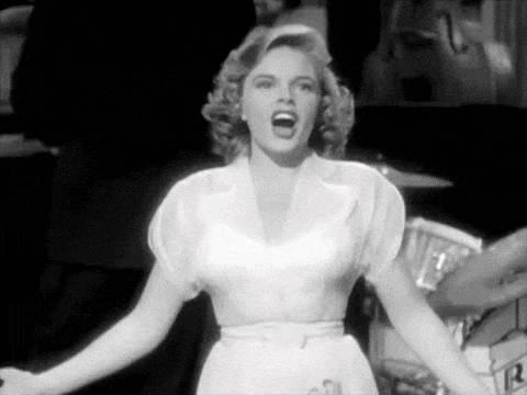 a black and white photo of a woman singing in front of a band .