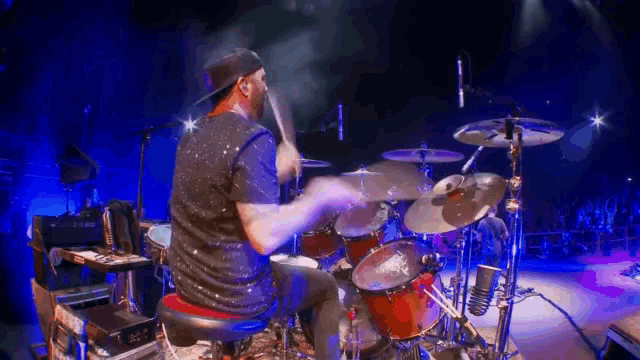 a man playing drums on a stage with a crowd watching
