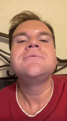 a man wearing a red shirt is making a face