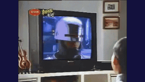 a man is watching a movie on a television with chinese writing on the screen