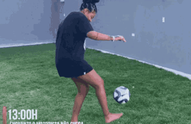 a woman kicking a soccer ball with the time of 13.00h on the bottom right