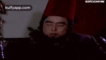 a man wearing a red hat is sitting on a couch .