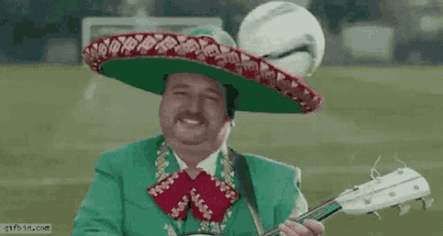 a man wearing a sombrero is playing a guitar while a soccer ball is in the background .