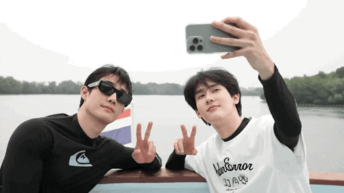 two men are taking a selfie and one has a shirt that says harbor
