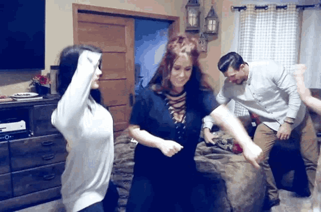 a group of people are dancing in a living room while a man watches .