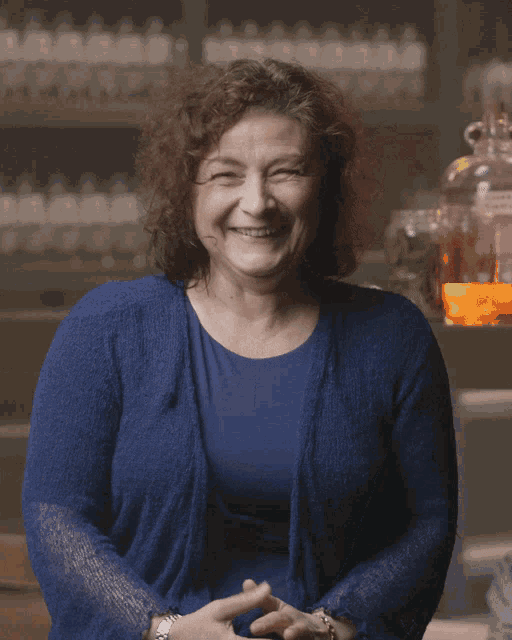 a woman wearing a blue sweater is laughing