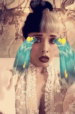 a woman with a bun and a nose ring is crying with blue birds on her face