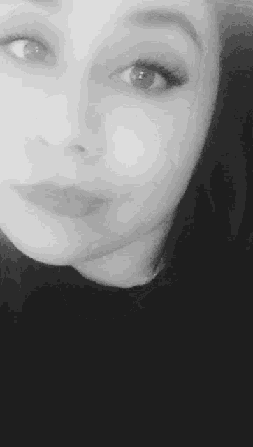 it is a black and white photo of a woman smiling .