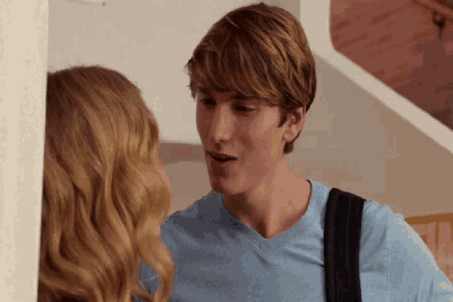 a man in a blue shirt is talking to a blonde woman