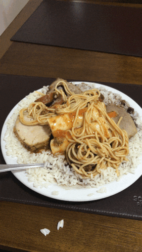 a white plate topped with spaghetti meat and rice with a fork