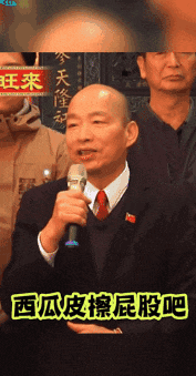 a man in a suit and tie is speaking into a microphone with chinese writing on the bottom