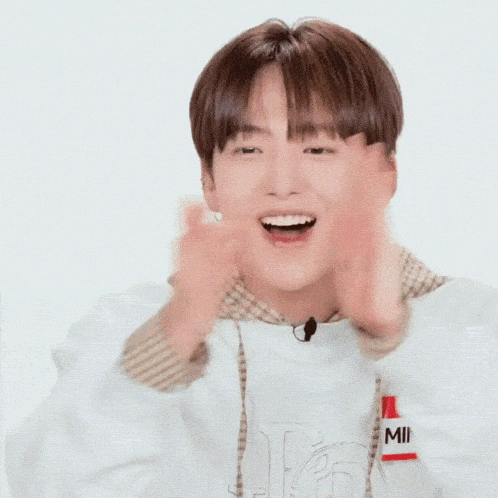 a young man wearing a name tag that says minjae is laughing with his eyes closed .