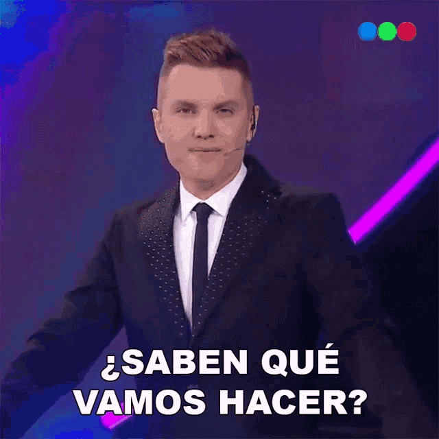 a man in a suit and tie says " saben que vamos hacer " on a purple background